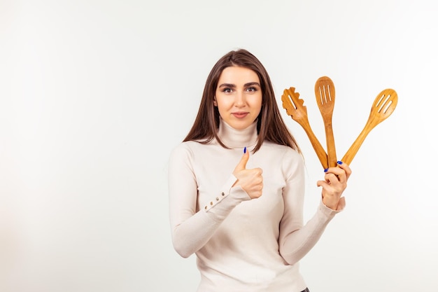 Cute lady holding wooden spoons and gesture thumb up