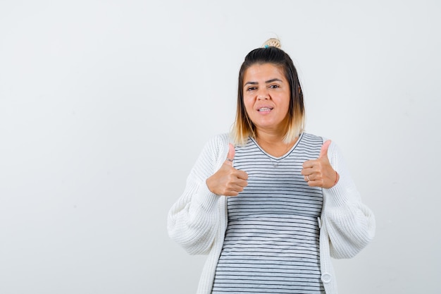 Free photo cute lady showing double thumbs up in t-shirt, cardigan and looking pleased , front view.