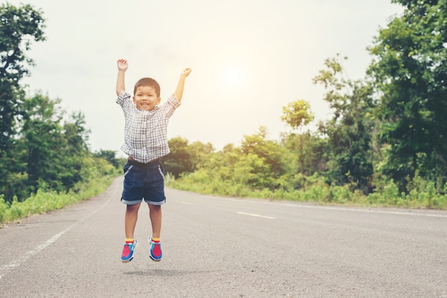 Cute little asian boy jumping on the road.