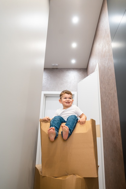 Cute little baby boy sitting on cardboard box