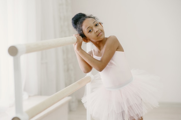 Free photo cute little ballerina in pink ballet costume. child in a pointe shoes is dancing in the room. kid in dance class.