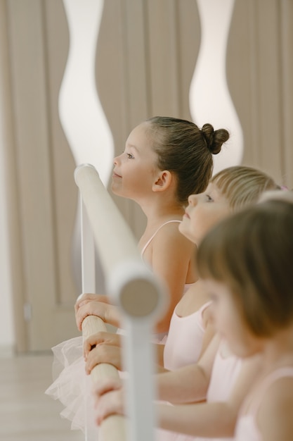 Free Photo cute little ballerinas in pink ballet costume. children in a pointe shoes is dancing in the room. kid in dance class.