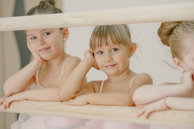 Free photo cute little ballerinas in pink ballet costume. children in a pointe shoes is dancing in the room. kid in dance class.