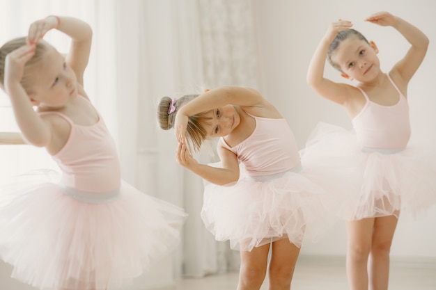 Cute little ballerinas in pink ballet costume. Children in a pointe shoes is dancing in the room