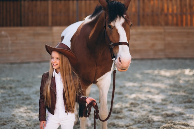 Cute little blonde girl with horse at ranch