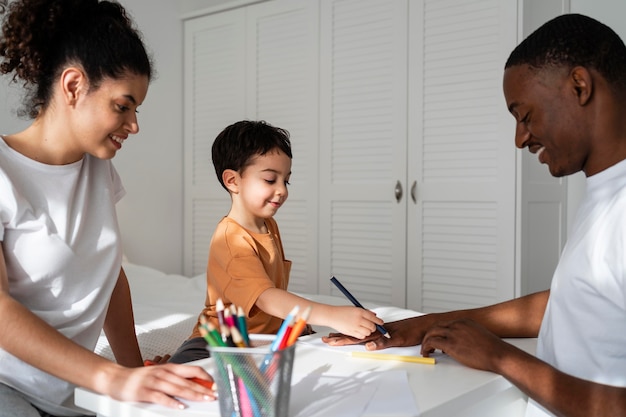 Cute little boy drawing his father hand on paper while smiling