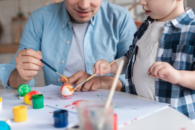 Free photo cute little boy learning how to paint eggs for easter