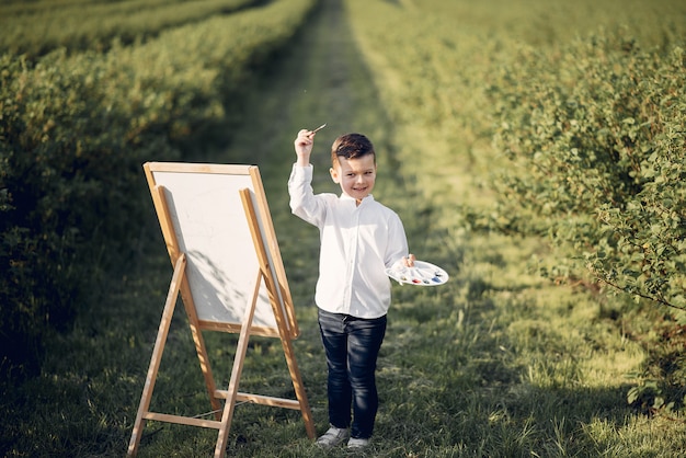 Cute little boy painting in a park