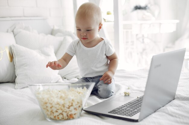 Cute little boy playing with a laptop on a bed