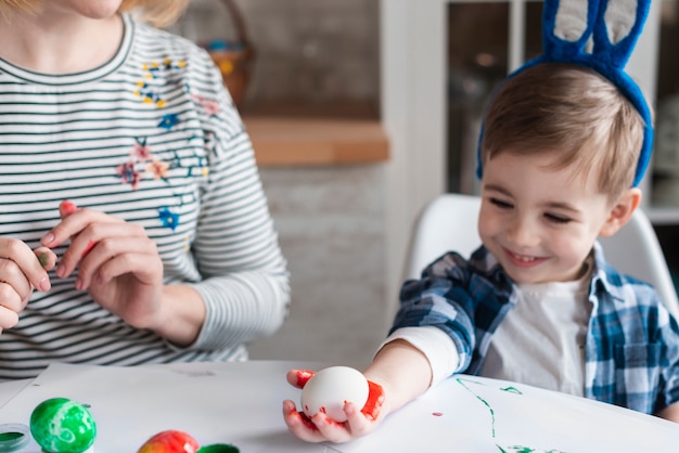 Free Photo cute little boy with bunny ears holding an egg