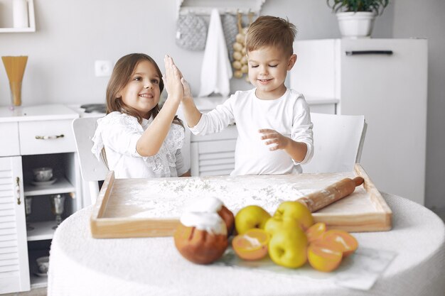 Cute little children sitting in a kitchen with dough