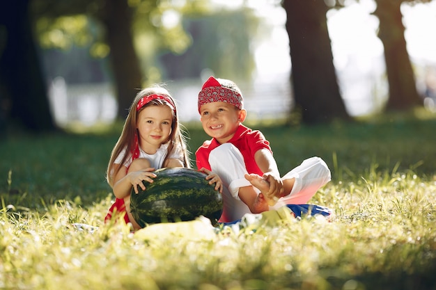 Free photo cute little children with watermelons in a park