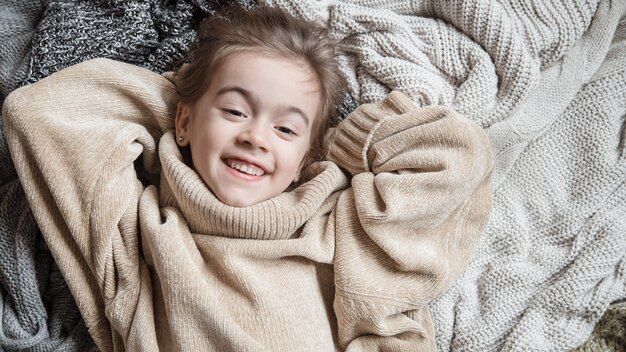 Cute little fun girl in a knitted sweater