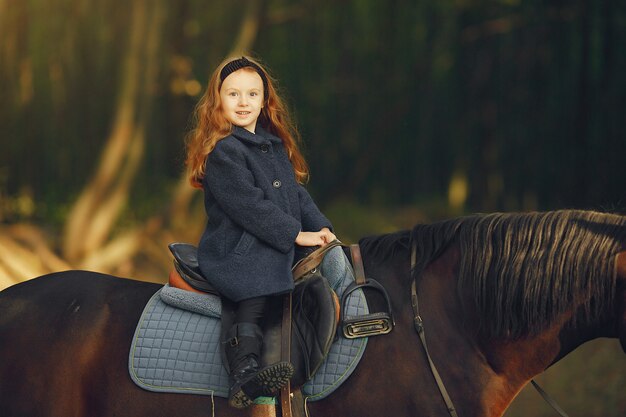 Cute little girl in a autumn field with horse