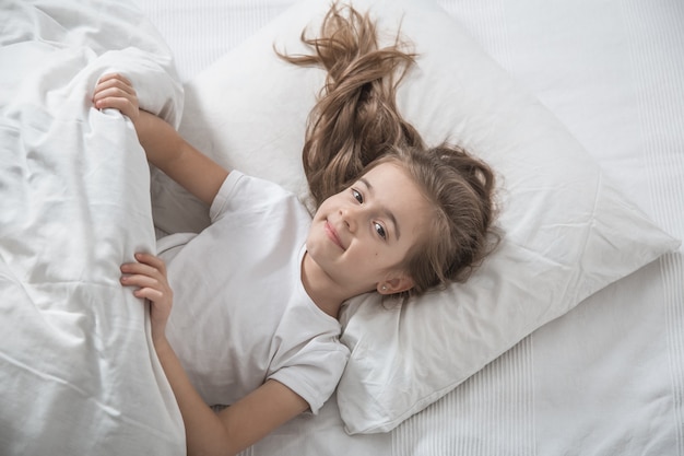 Cute little girl in bed woke up in the morning