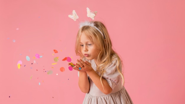 Cute little girl in costume blowing confetti