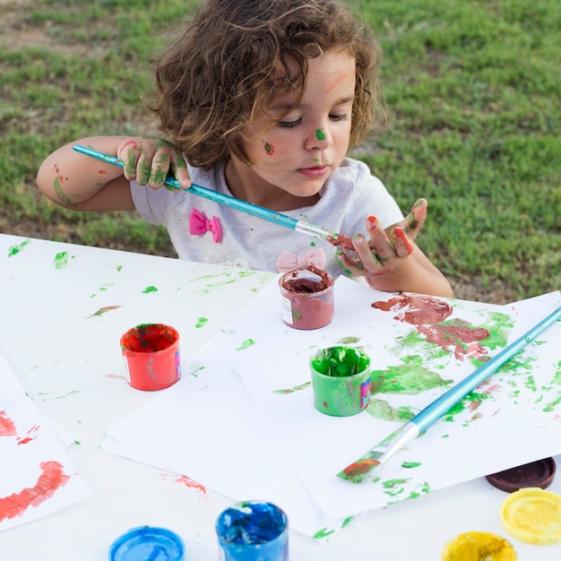 Free photo cute little girl drawing painting on canvas in park