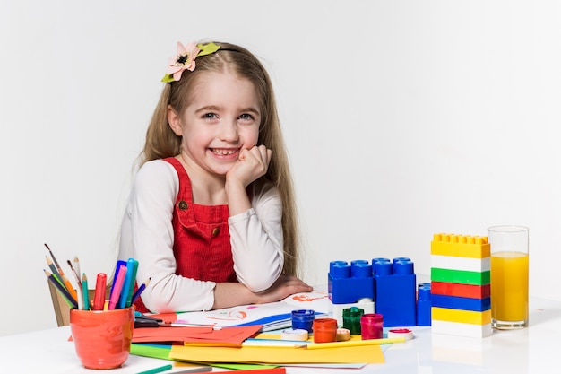 Cute little girl drawing with paint and paintbrush at home