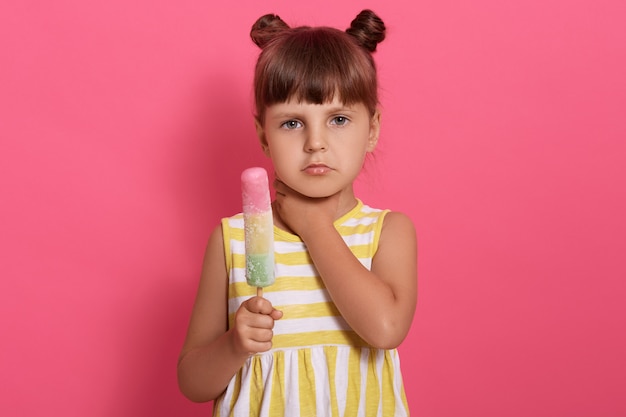 Cute little girl eating ice cream and has sore throat