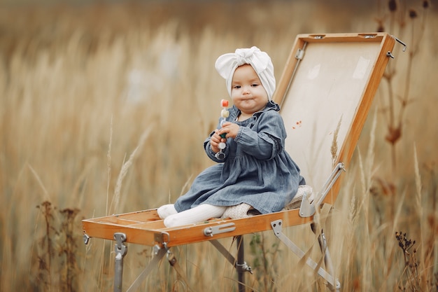 Cute little girl painting in a autumn field