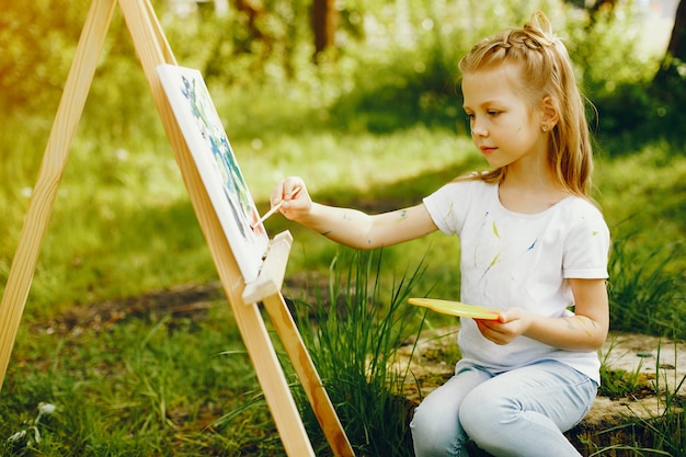 Free photo cute little girl painting in a park