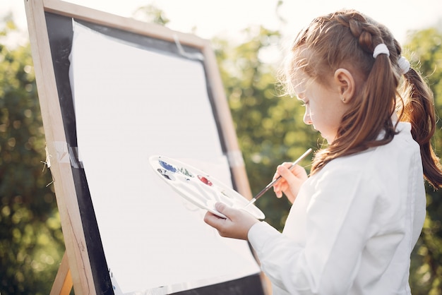 Free Photo cute little girl painting in a park