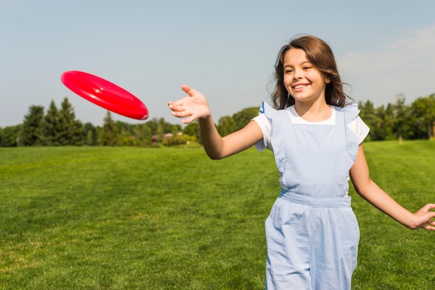 Free photo cute little girl playing with red frisbee