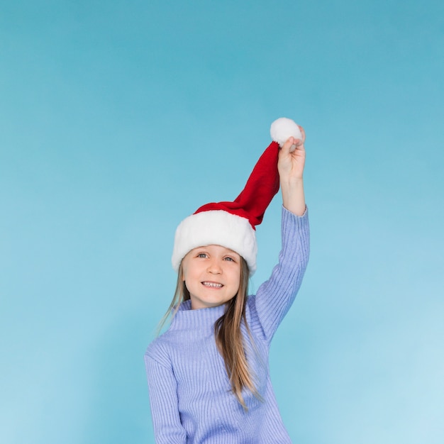 Free photo cute little girl playing with a santa claus hat