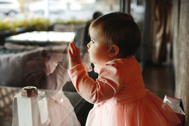 Free photo cute little girl puts her hands on the window