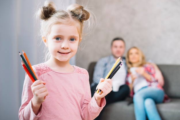 Cute little girl showing colorful drawing pencils