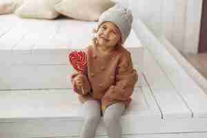 Free photo cute little girl sitting and eating candy