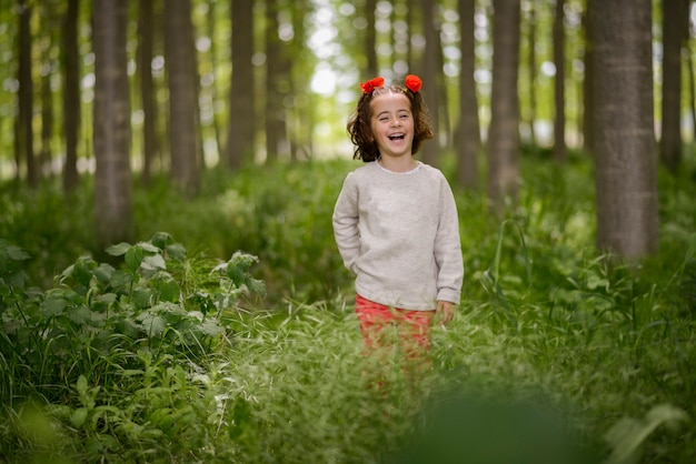 Cute little girl with four years old having fun in a poplar forest