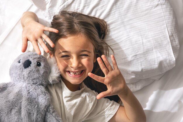 Cute little girl with her favorite soft toy in bed in the morning