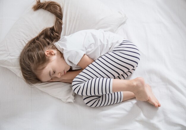 Cute little girl with long hair sleeping in bed