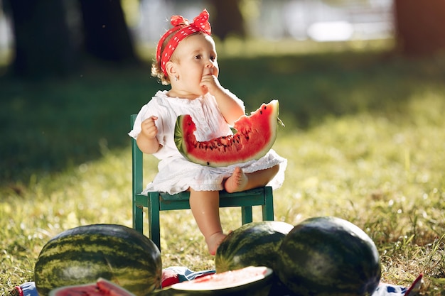 Free photo cute little girl with watermelons in a park