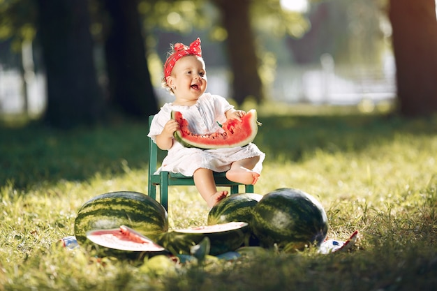 Free photo cute little girl with watermelons in a park