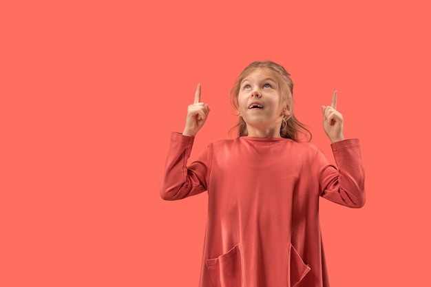 Cute little surprised girl in coral dress with long hair smiling to camera