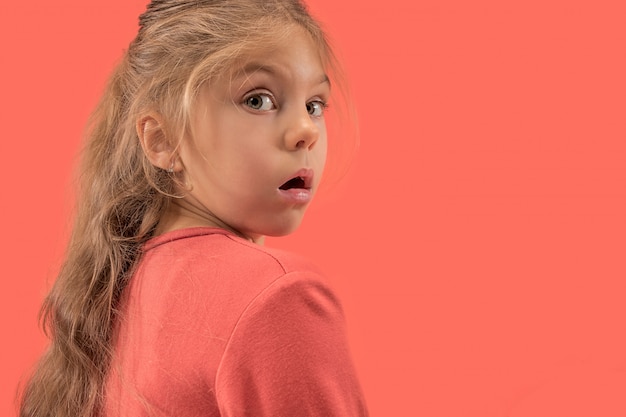 Free photo cute little surprised girl in coral dress with long hair smiling to camera