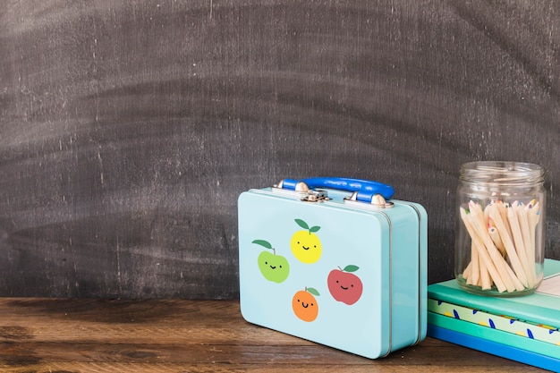 Free photo cute lunchbox near pencils and notepads