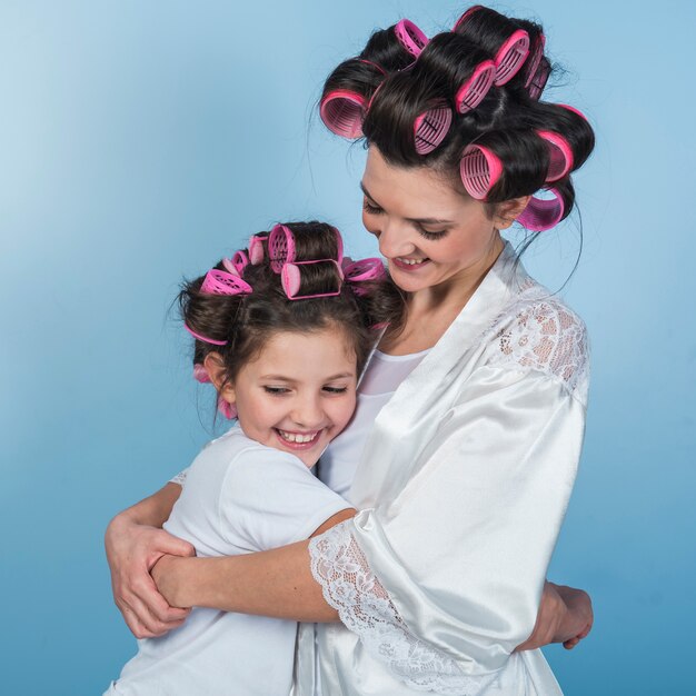 Cute mother and daughter in curlers hugging