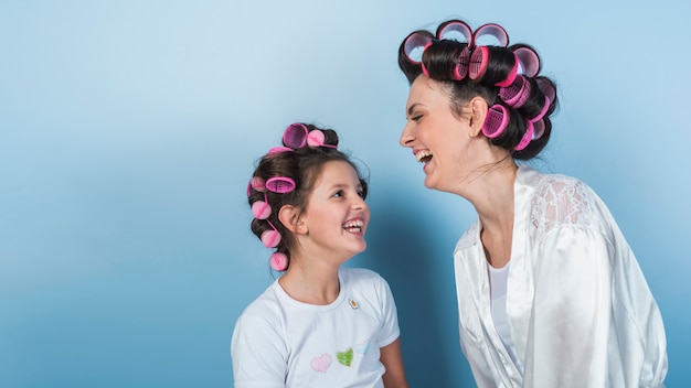 Cute mother and daughter in curlers laughing