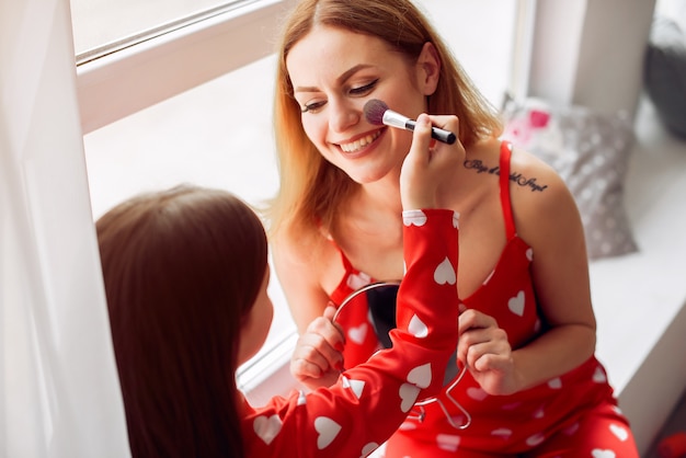 Free photo cute mother and daughter at home in a pajamas