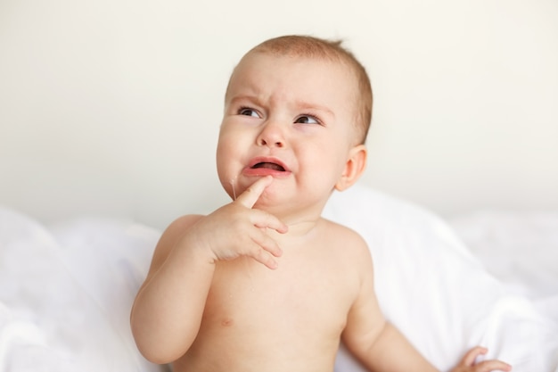 Free photo cute nice little baby woman crying lying with her mom on bed at home.