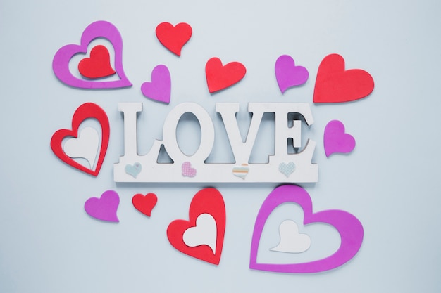 Free photo cute paper hearts around love writing