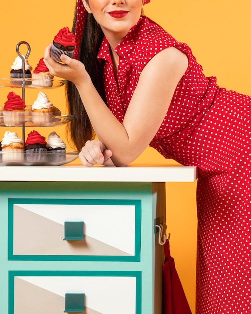 Free Photo cute pinup girl standing next to some cupcakes