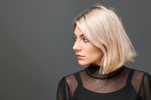 Free Photo cute positive young caucasian female wearing trendy black top and transparent dress having dreamy pensive facial expression, making plans for christmas holidays, looking away and smiling joyfully