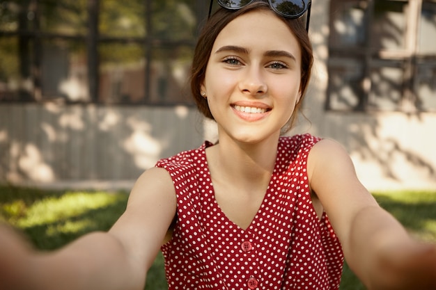 Free photo cute pretty girl with broad charming smile taking selfie using electronic gadget.