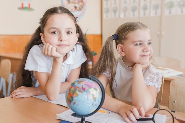 Free photo cute schoolgirls sitting at desk