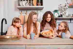 Free photo cute sisters standing in a kitchen and eats buns