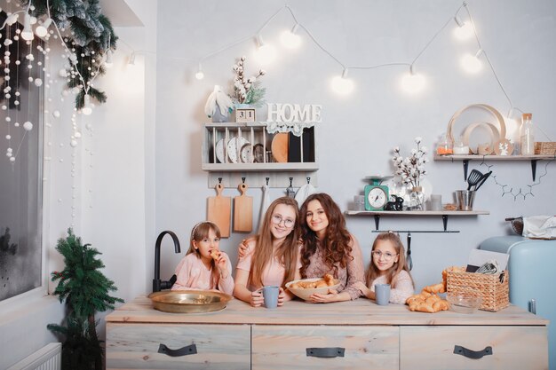 Cute sisters standing in a kitchen and eats buns